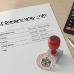 Document titled “LLC Company Setup – UAE” with red approval stamp, calculator, and pen on office desk.