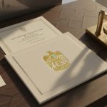 Official UAE documents, a gold emblem folder, a gold pen, and a traditional embossing stamp arranged on a wooden desk.