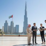 Business professionals meeting in Downtown Dubai with Burj Khalifa and UAE flag behind them, representing trademark and business growth.